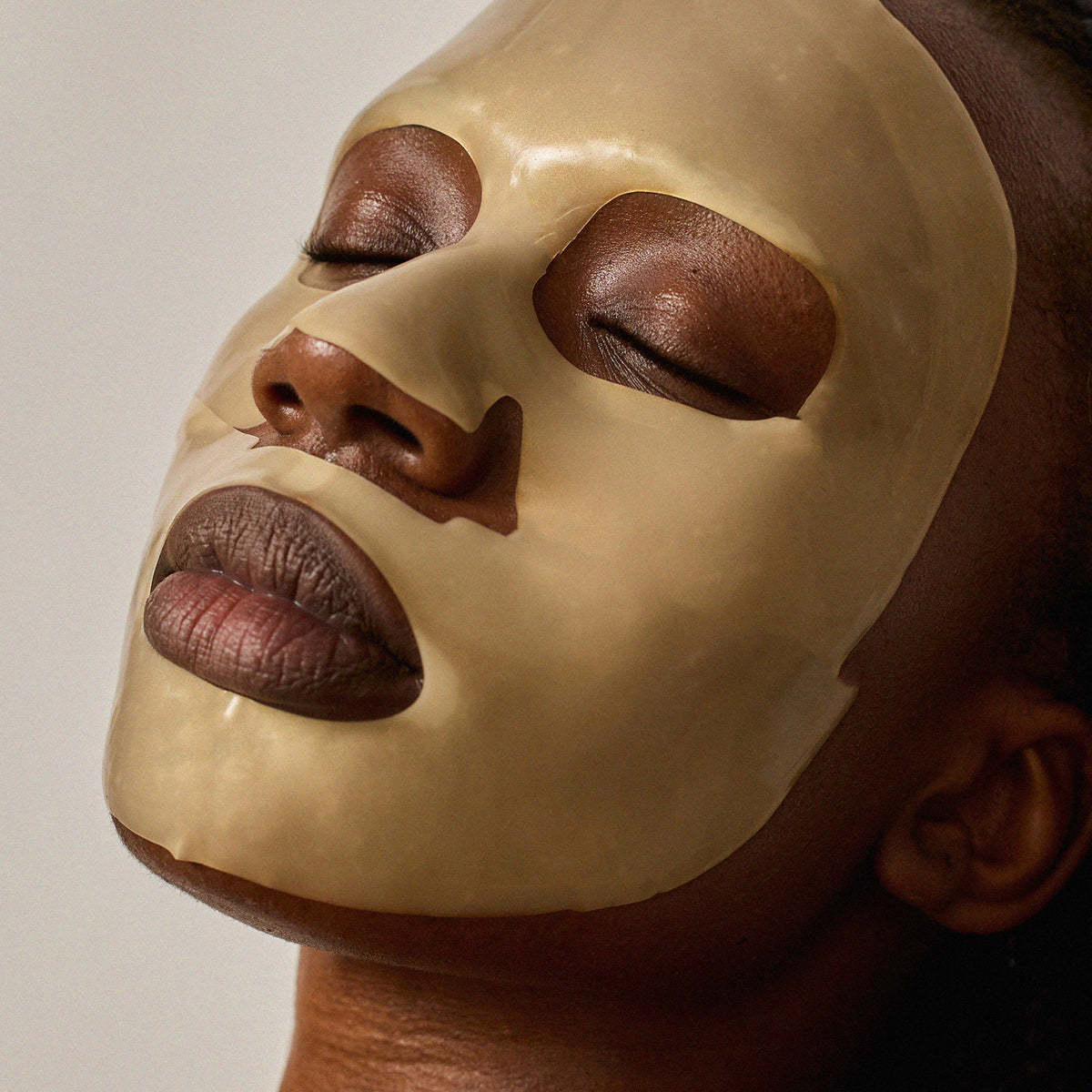 A close-up of a person wearing Radford Fix -the face mask on their face, with their eyes closed and head tilted back against a plain light background.