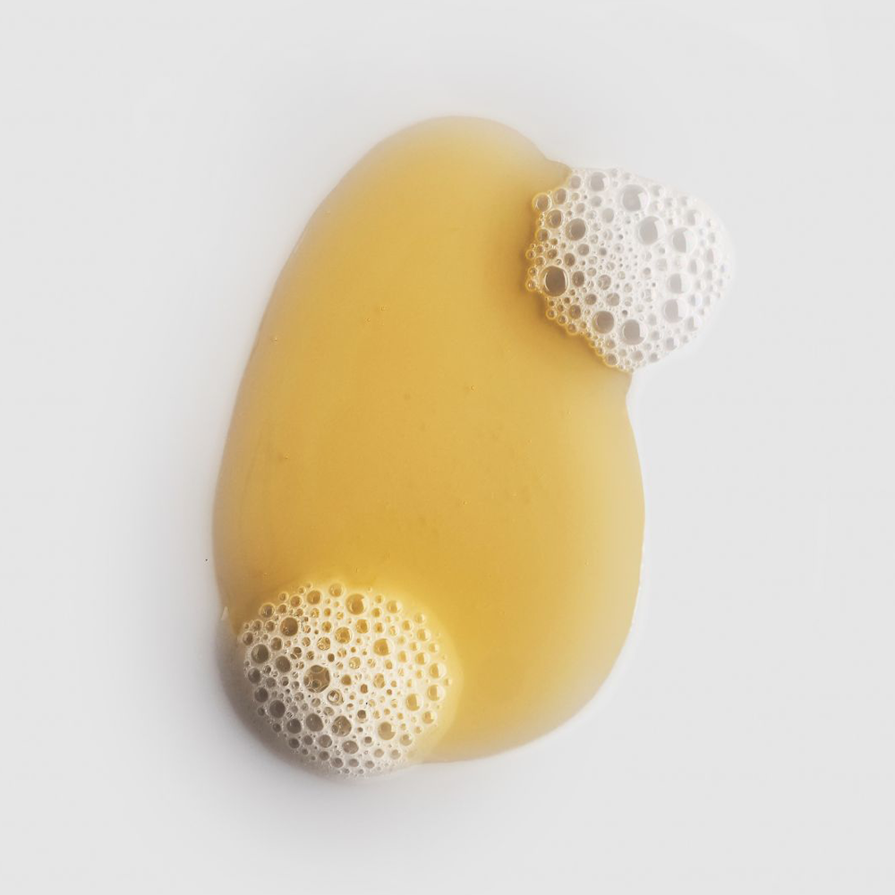 A bar of soap with bubbly white foam caps on a clean white background.