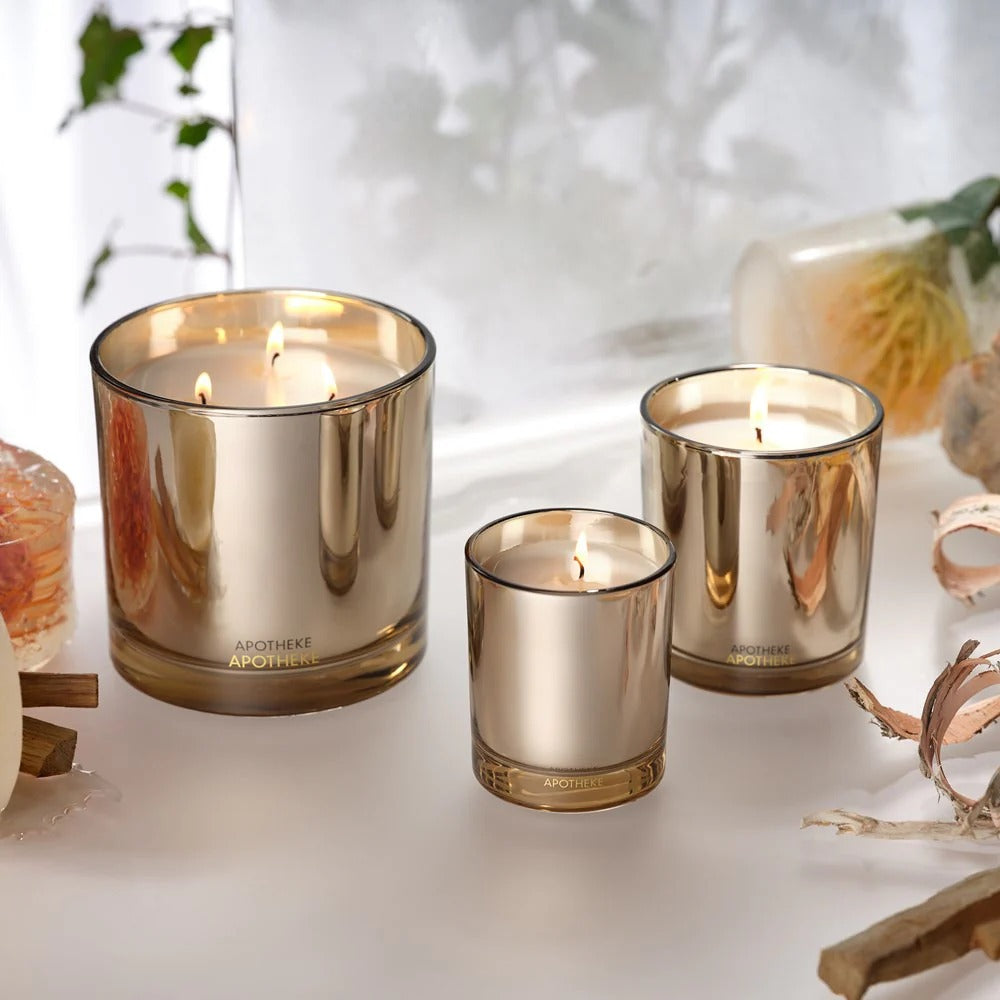 Three gold-colored candles on a white surface with a blurred background