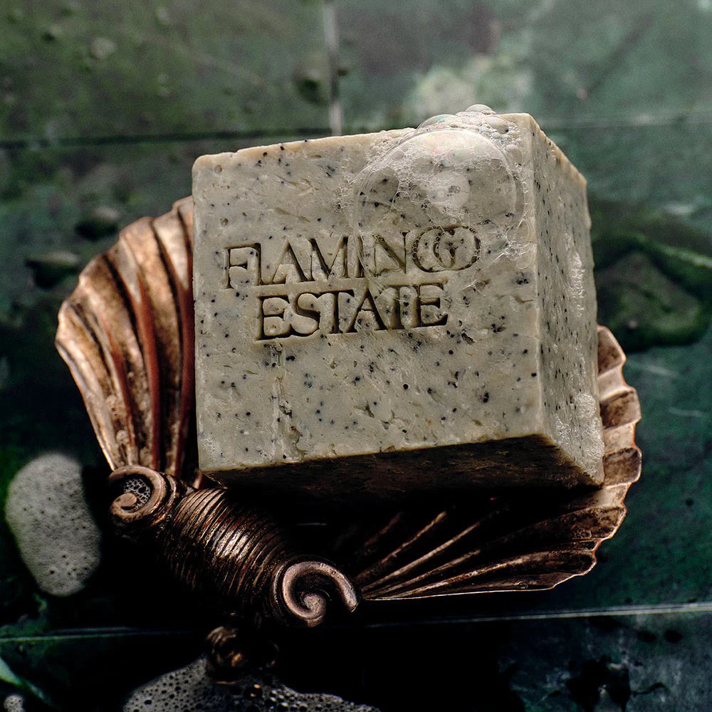 Peppermint bar of soap with 'Flamingo Estate' branding on a decorative holder against a green background.