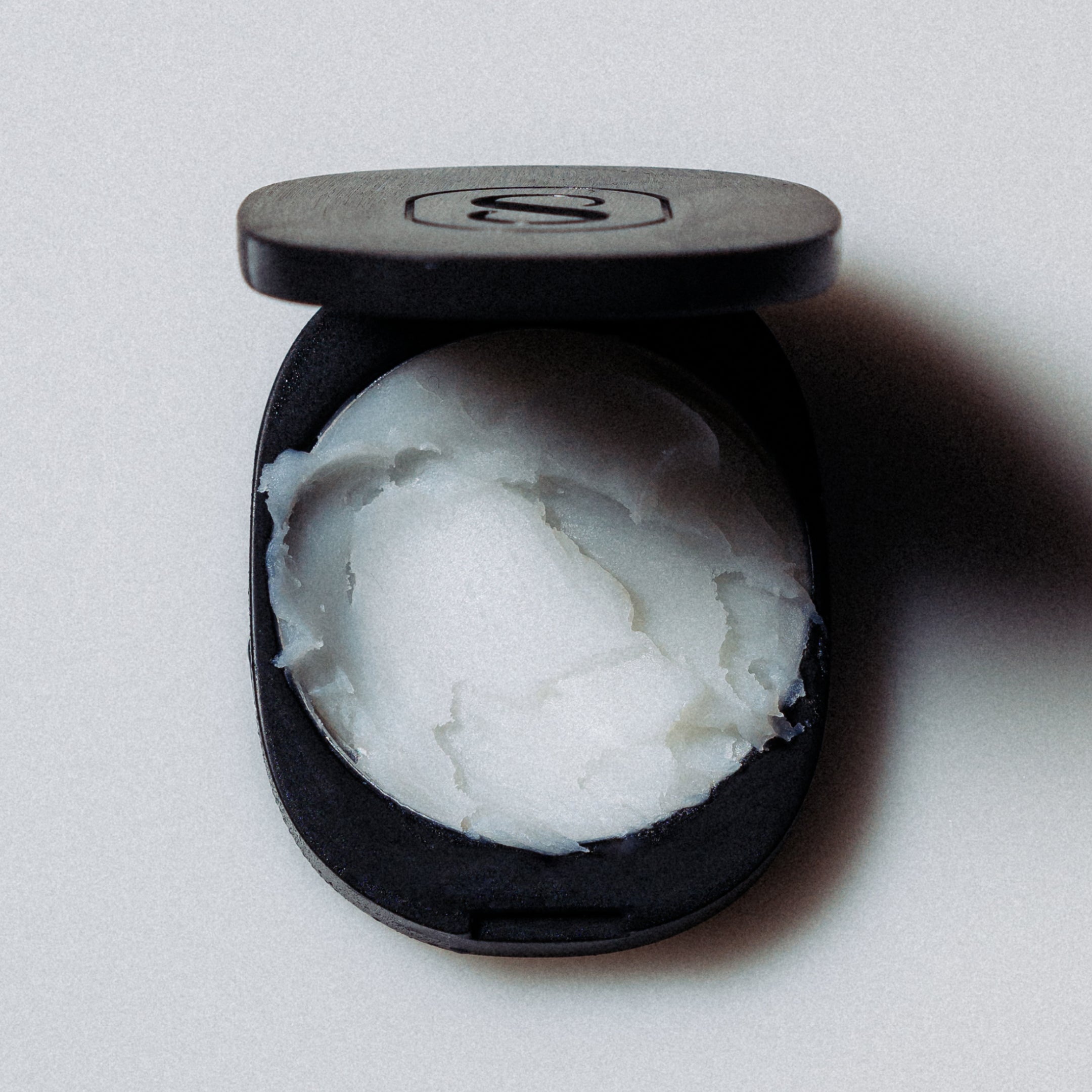 Black container with white cream on a light gray background