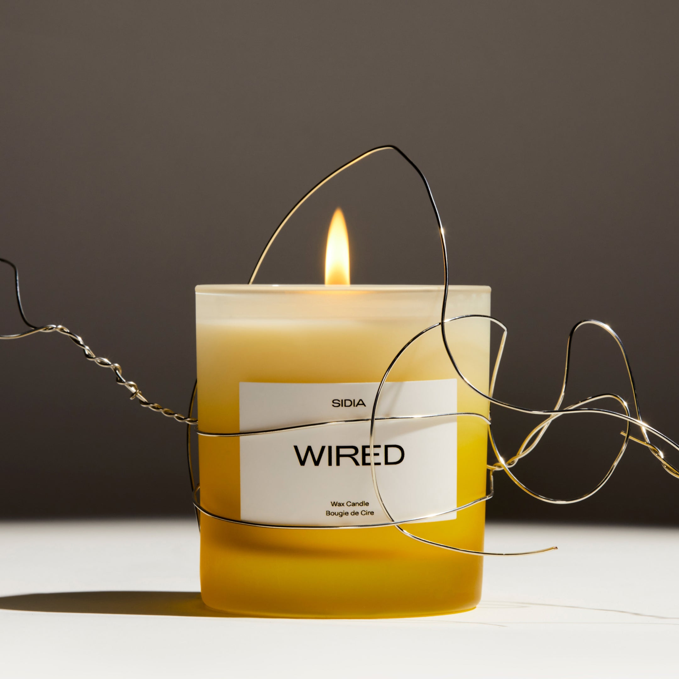 SIDIA candle in the scent "WIRED" wrapped in wire in front of a white and gray background