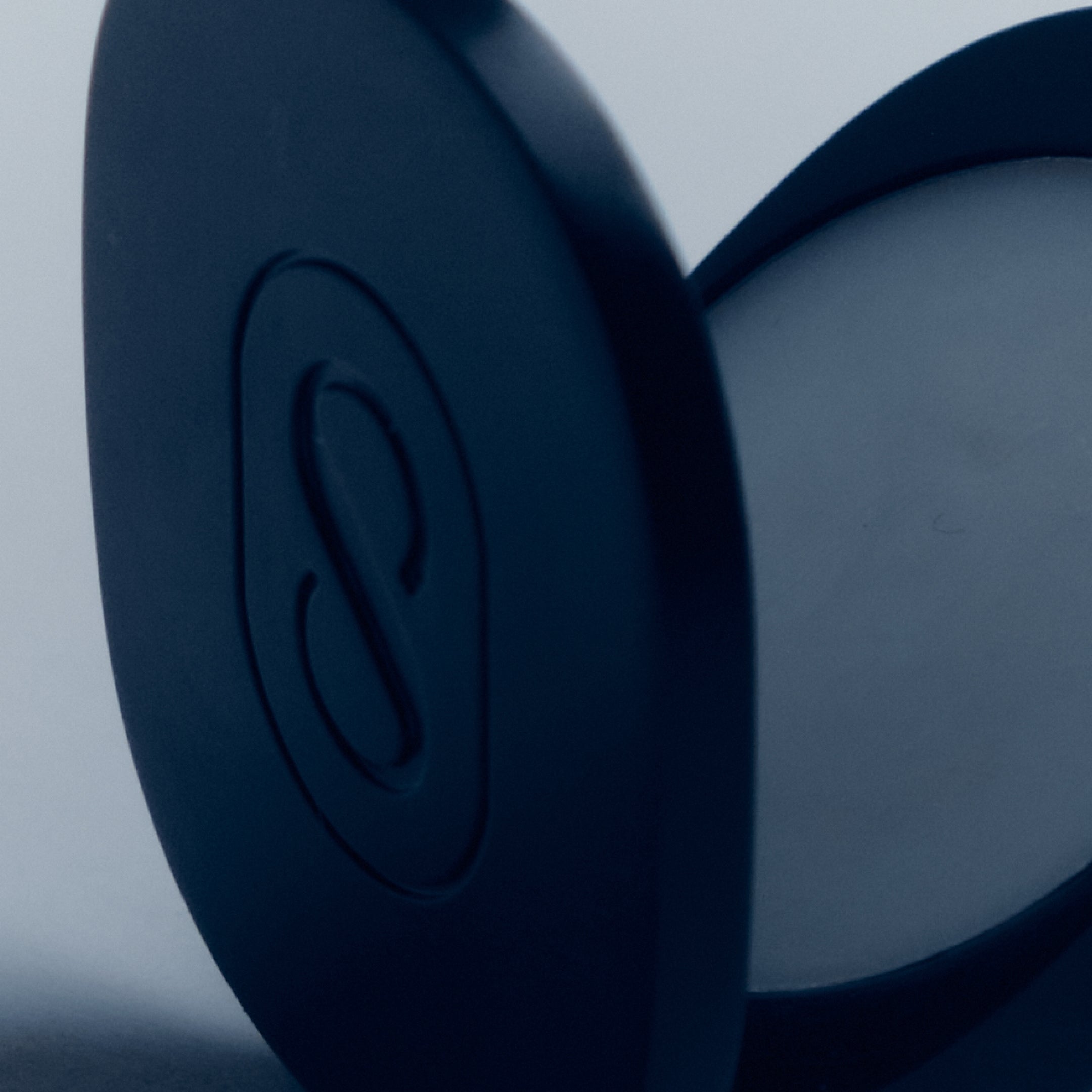 Close-up of a blue earbud with a brand logo on a light gray background