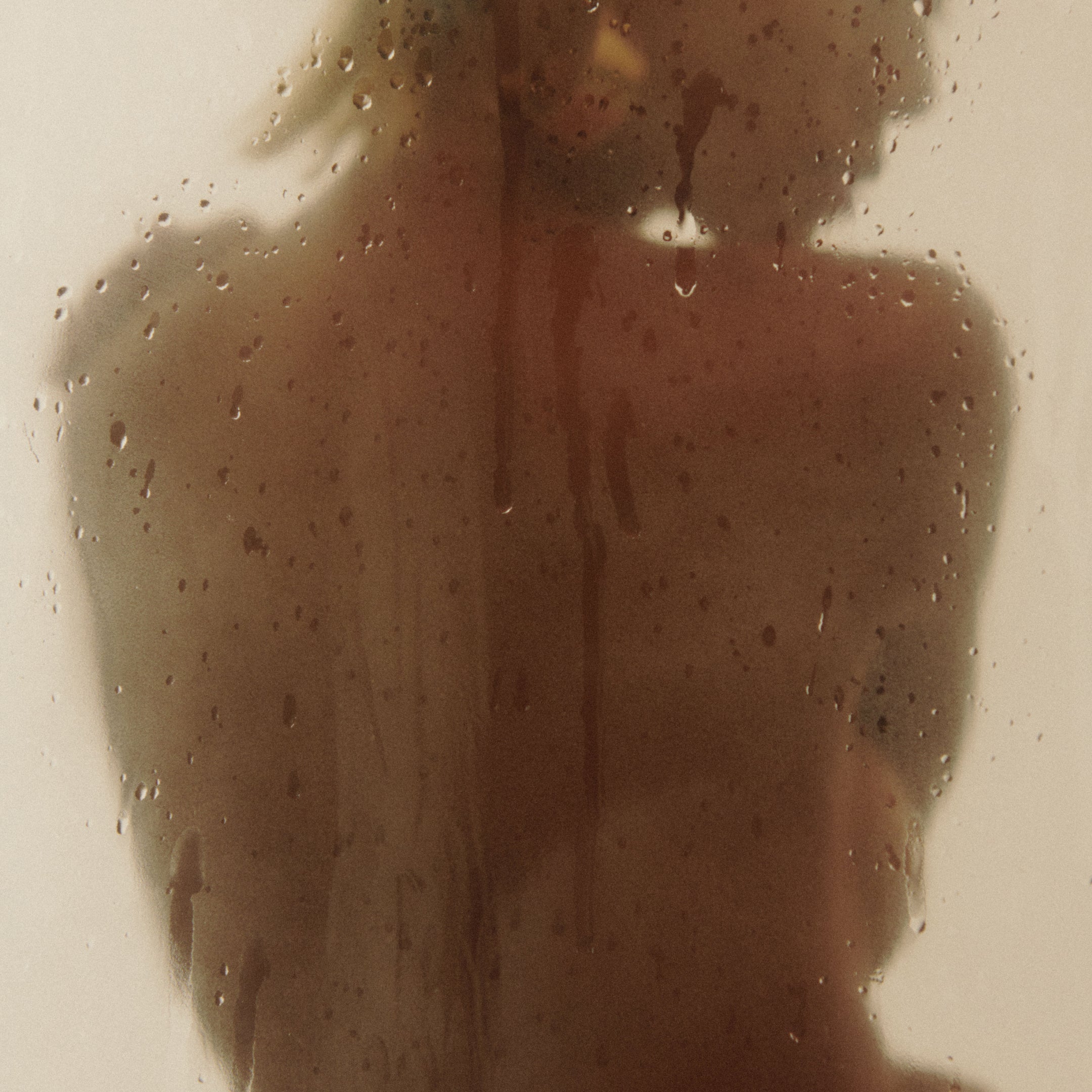 A persons back behind steamy glass