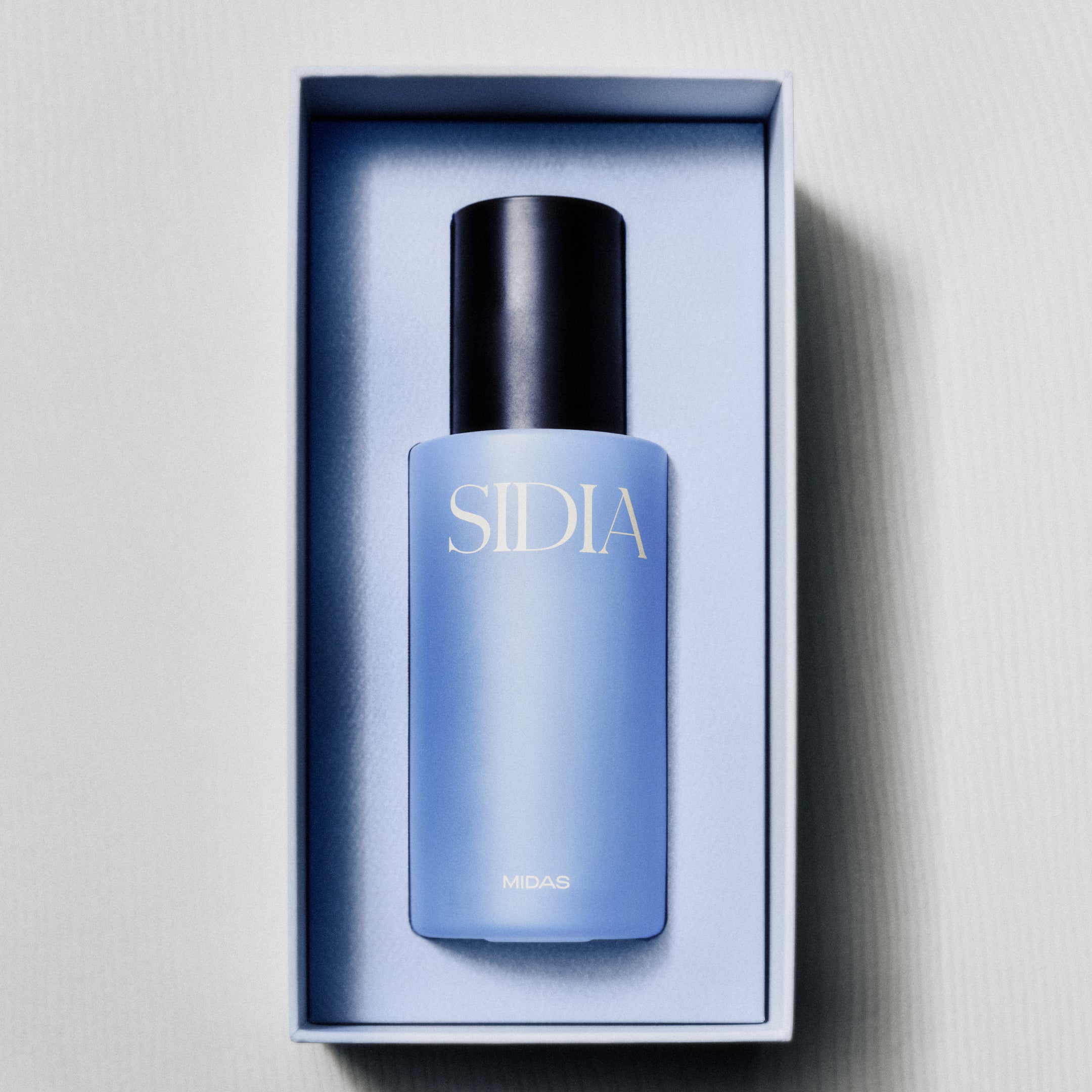 Blue skincare bottle with black cap in a box on a light gray background