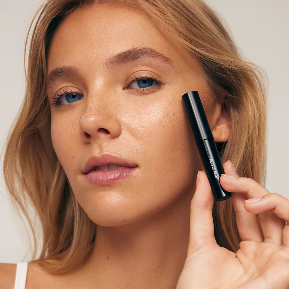 Woman holding product near her face with a white background
