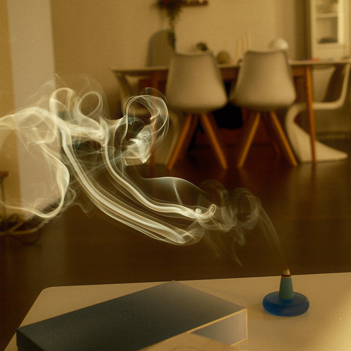 Incense cone with smoke in a room with chairs and a table.