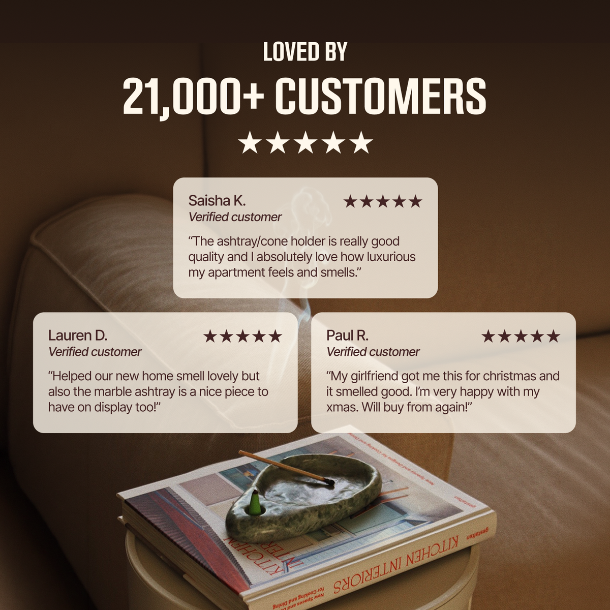 Promotional graphic with the text 'LOVED BY 21,000+ CUSTOMERS' above four customer review cards. Below the cards, a marble ashtray with a small green incense stick rests on a stack of books in a living room setting.