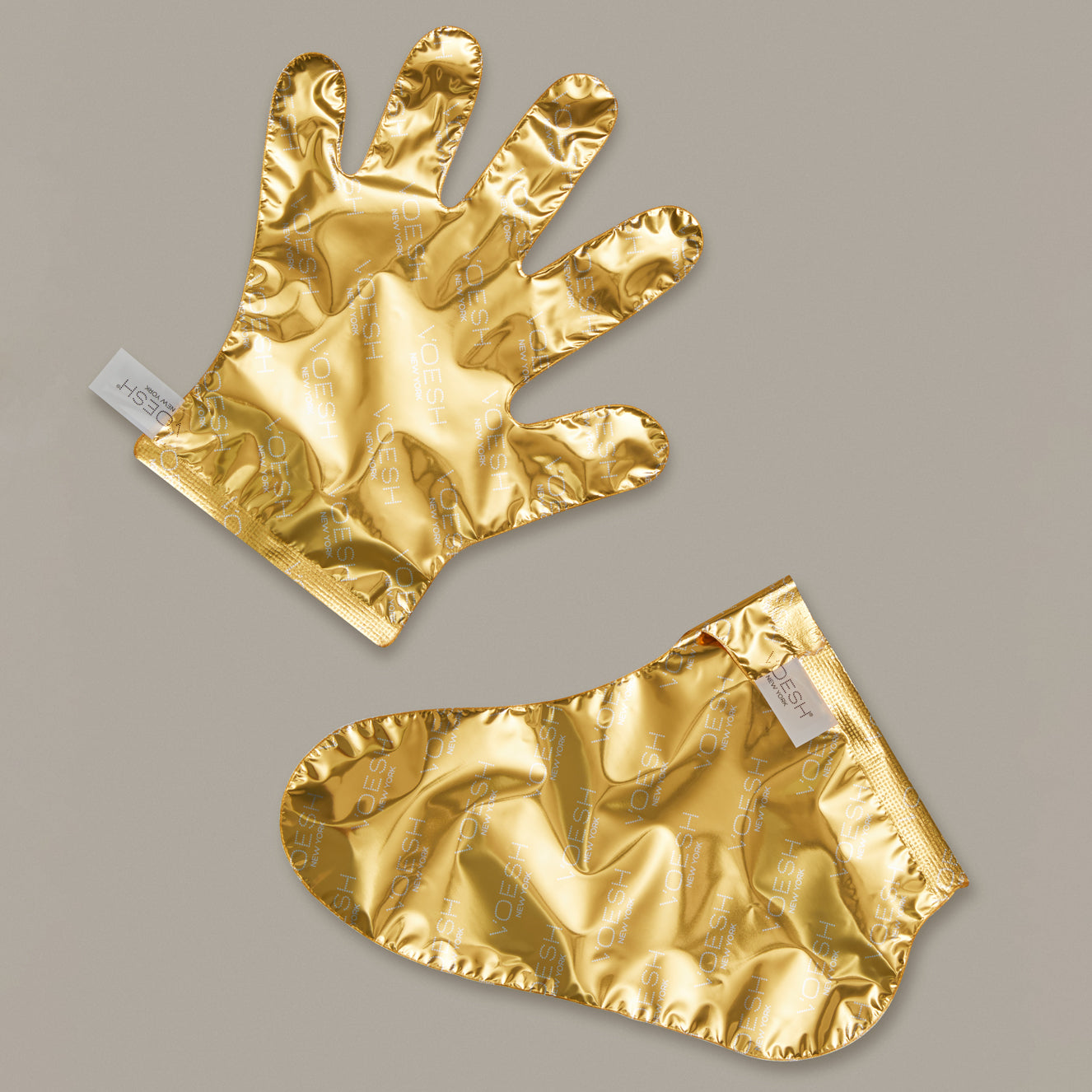 Two gold foil gloves on a gray background