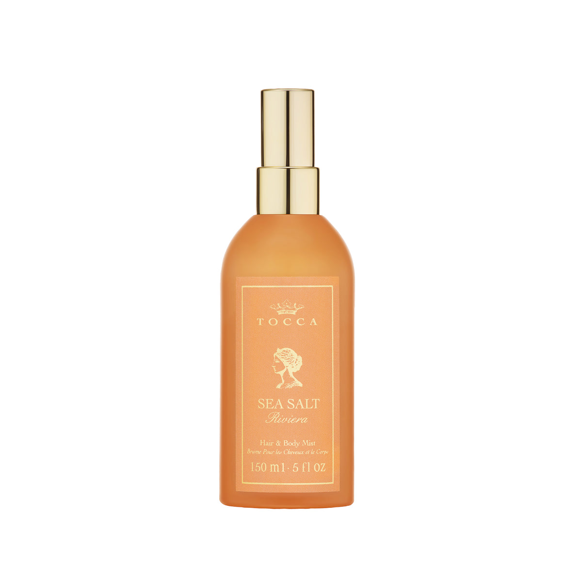A bottle of TOCCA Sea Salt Riviera - Hair and Body Mist in a warm amber-orange color with a shiny gold spray nozzle, centered on a plain white background.