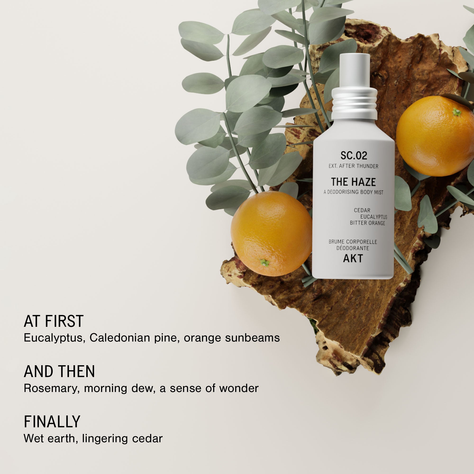 Bottle of AKT The Haze SC. 02 After Thunder is styled on a rustic wood slice with eucalyptus leaves and oranges against a light beige background. Text on the left reads 'AT FIRST', 'AND THEN', and 'FINALLY' with scent notes.