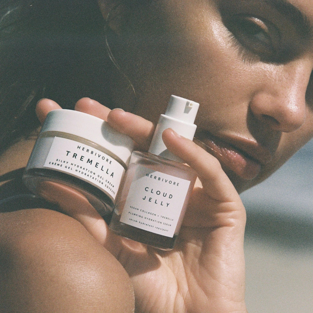 Person holding two Herbivore products, a jar and a bottle, with a blurred background.