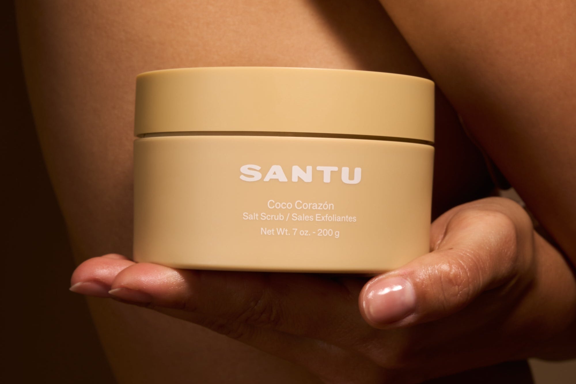 Person holding a beige jar labeled 'SANTU' against a neutral background