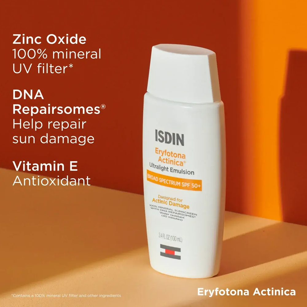 ISDIN Eryfotona Actinica Ultra Light Emulsion SPF 50+ sunscreen bottle on a warm orange and beige background with promotional text highlighting zinc oxide, DNA repairosomes, vitamin E, and antioxidant benefits.