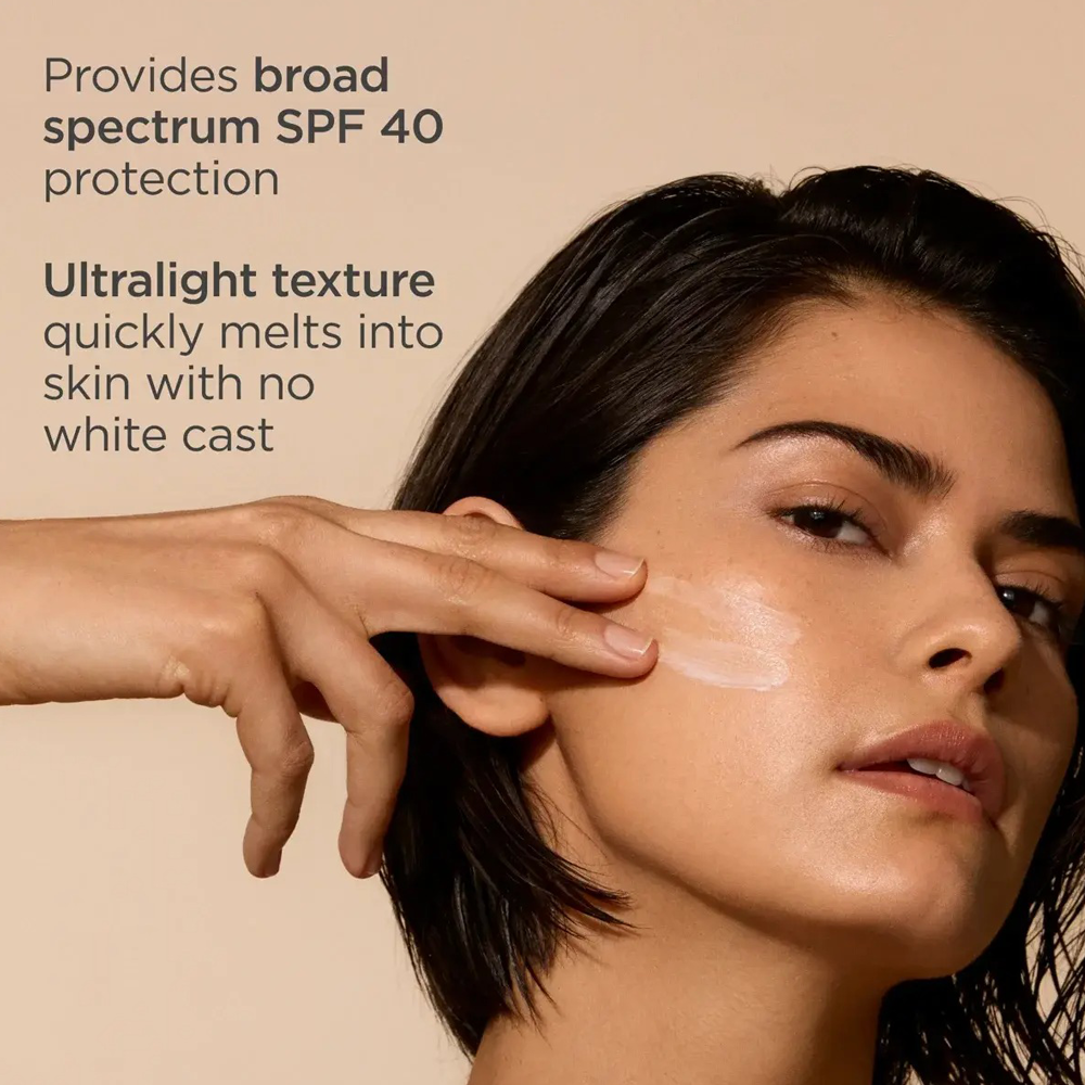 Close-up of a woman applying a translucent cream sunscreen product to her cheek, with text on the left stating it provides broad spectrum SPF 40 protection and has an ultralight texture that melts into skin without a white cast.