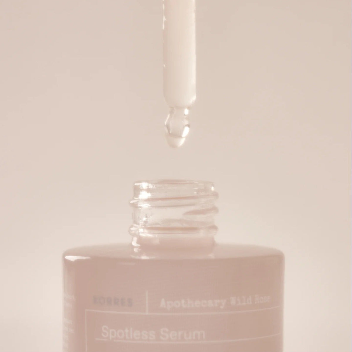 Serum bottle labeled 'Spotless Serum' with a dropper on a light pink background