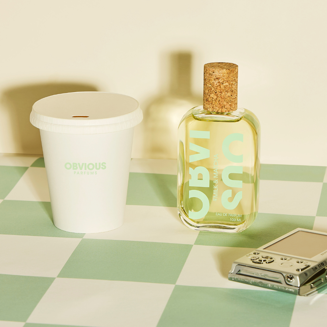 Fragrance bottle with cork cap and a matcha latte on a checkered surface