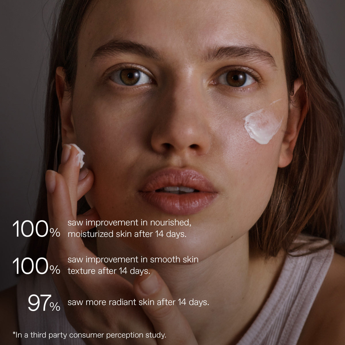 Close-up of a woman applying or spreading a white cream on her cheek, with overlaid text claiming skin improvement after 14 days. No packaged product is visible.