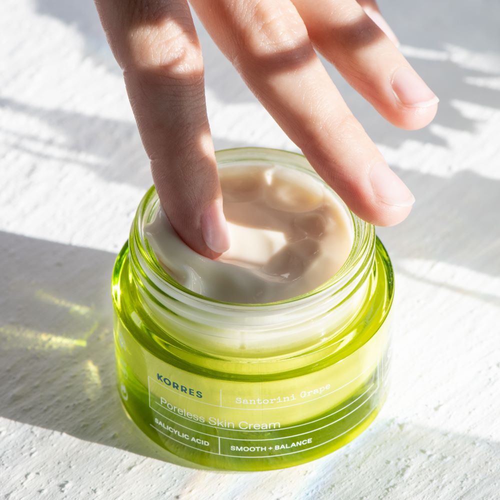 Hand in a jar of Korres skin cream on a light background