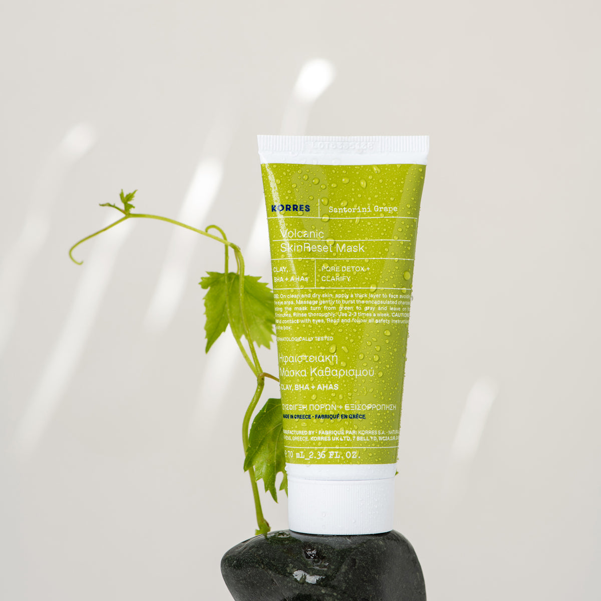 Green skincare tube with plant design on a white background