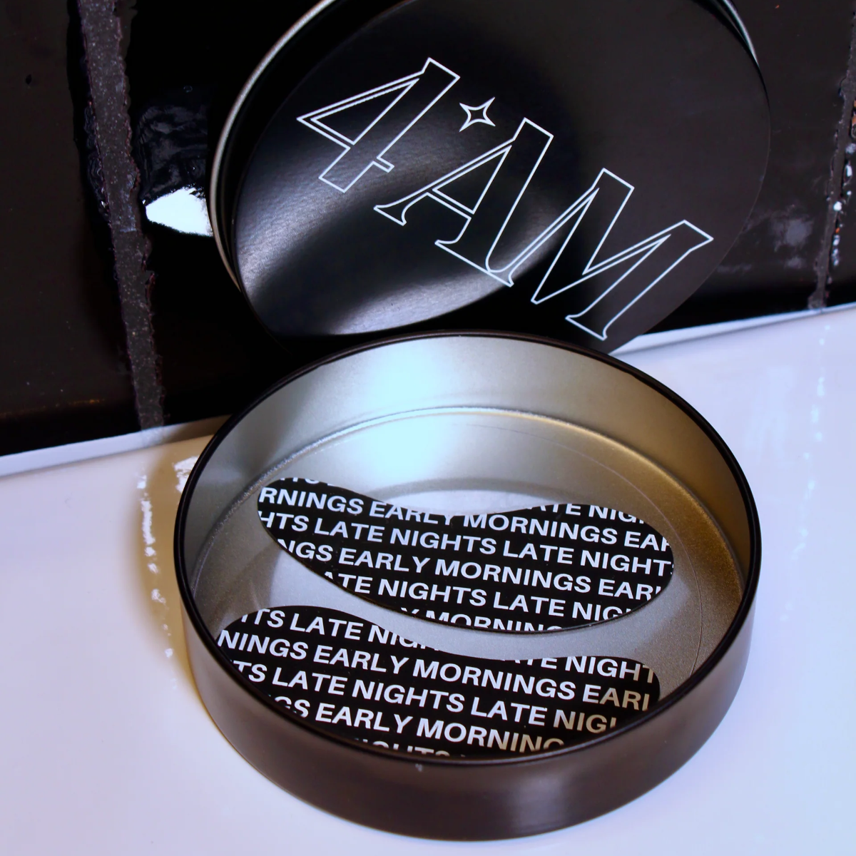 Metallic container with '4AM' branding on a dark background