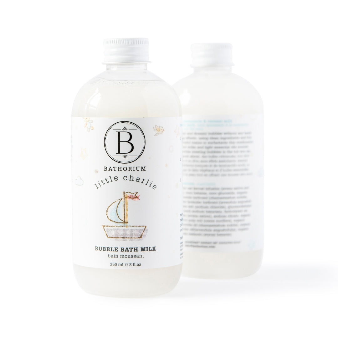 Two bottles of Bathorium Little Charlie Bubble Bath Milk on a white background, with the front bottle showing the white label with a sailboat illustration and the second bottle showing the back label.