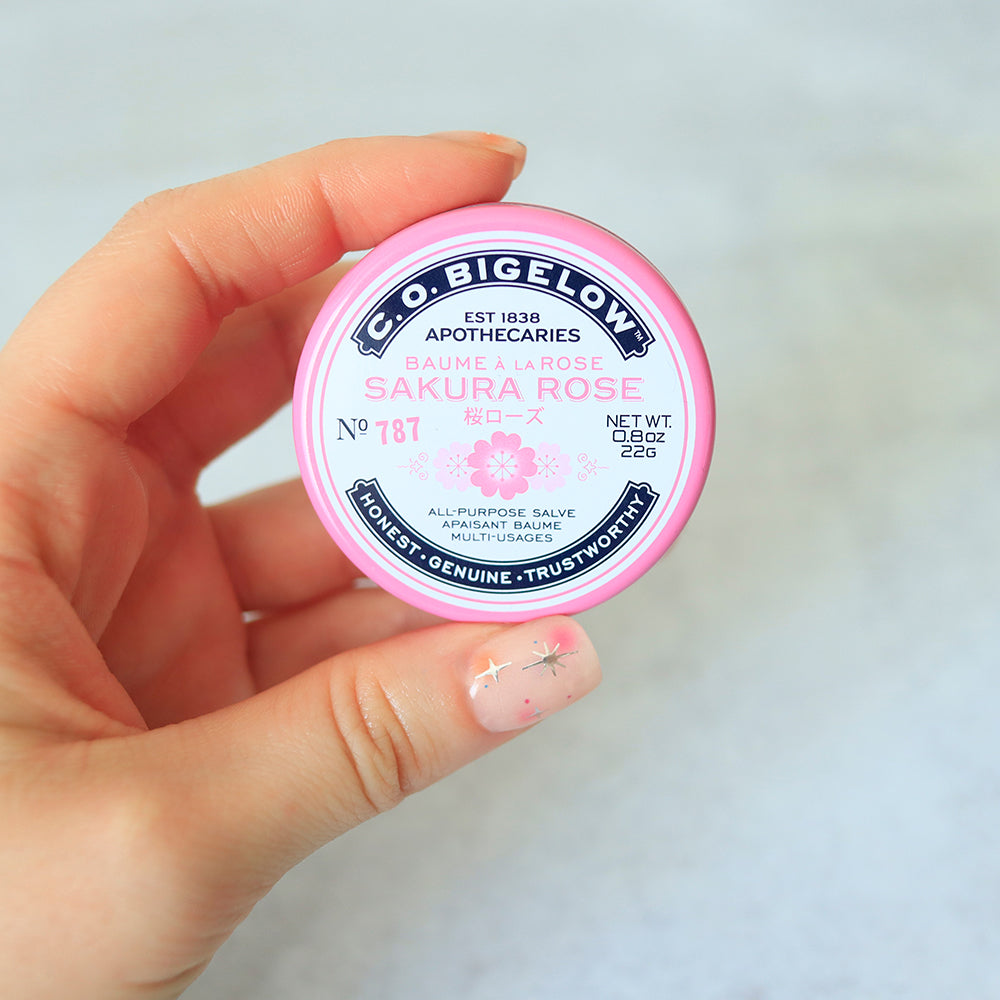 Hand holding a tin of C.O. Bigelow Sakura Rose Salve Tin.