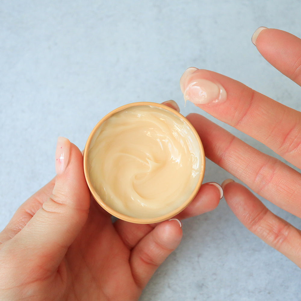 Hand holding a container of Coco Vanilla Salve against a light background
