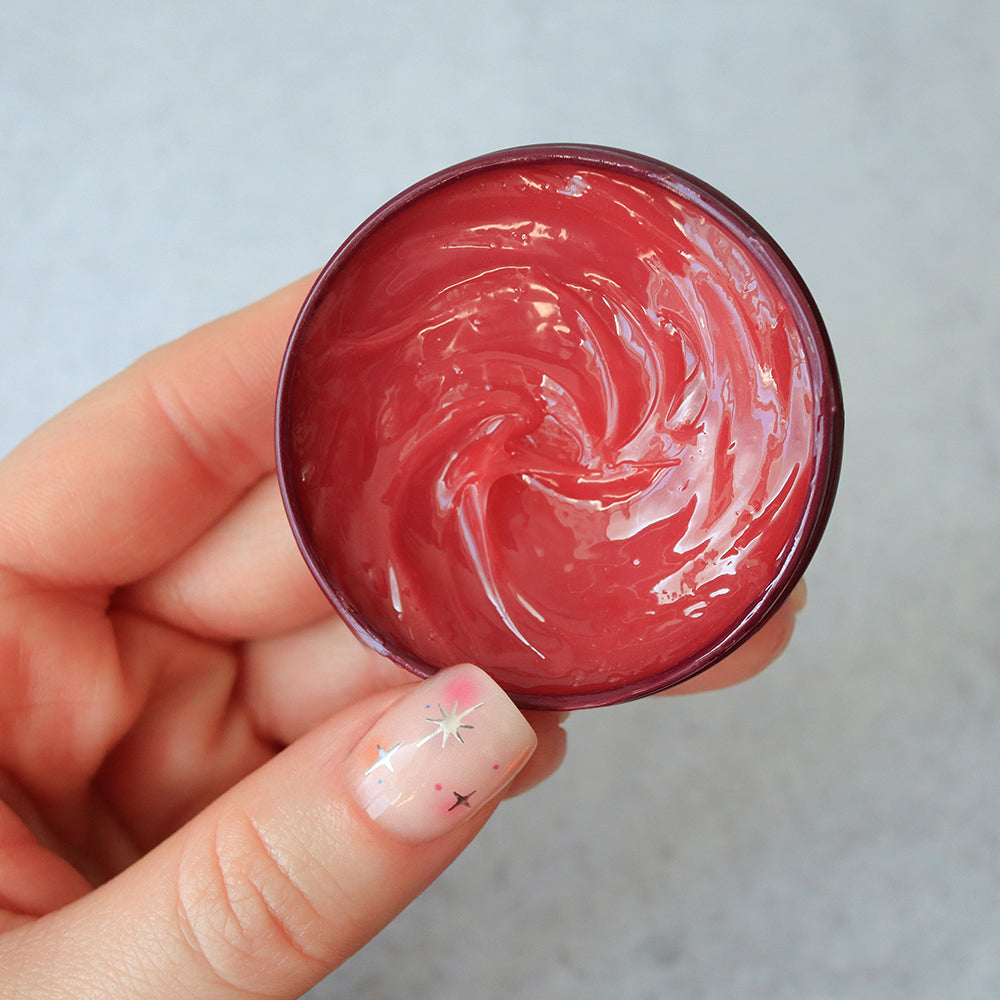Hand holding C.O. Bigelow Apple All-Purpose Salve Tin against a neutral background