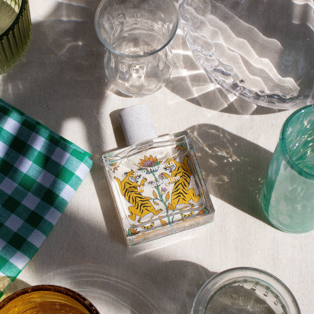 Table setting with glassware, a decorative tile, and a checkered cloth on a white surface.