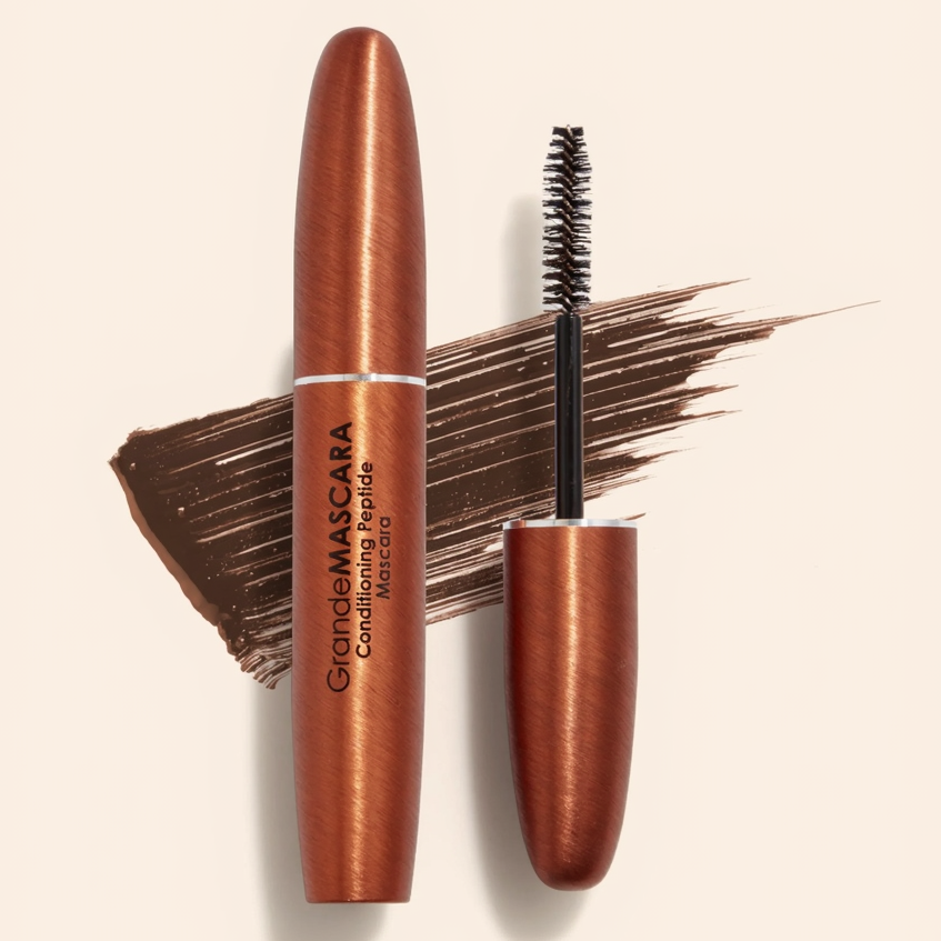 Bronze mascara with brush on a beige background