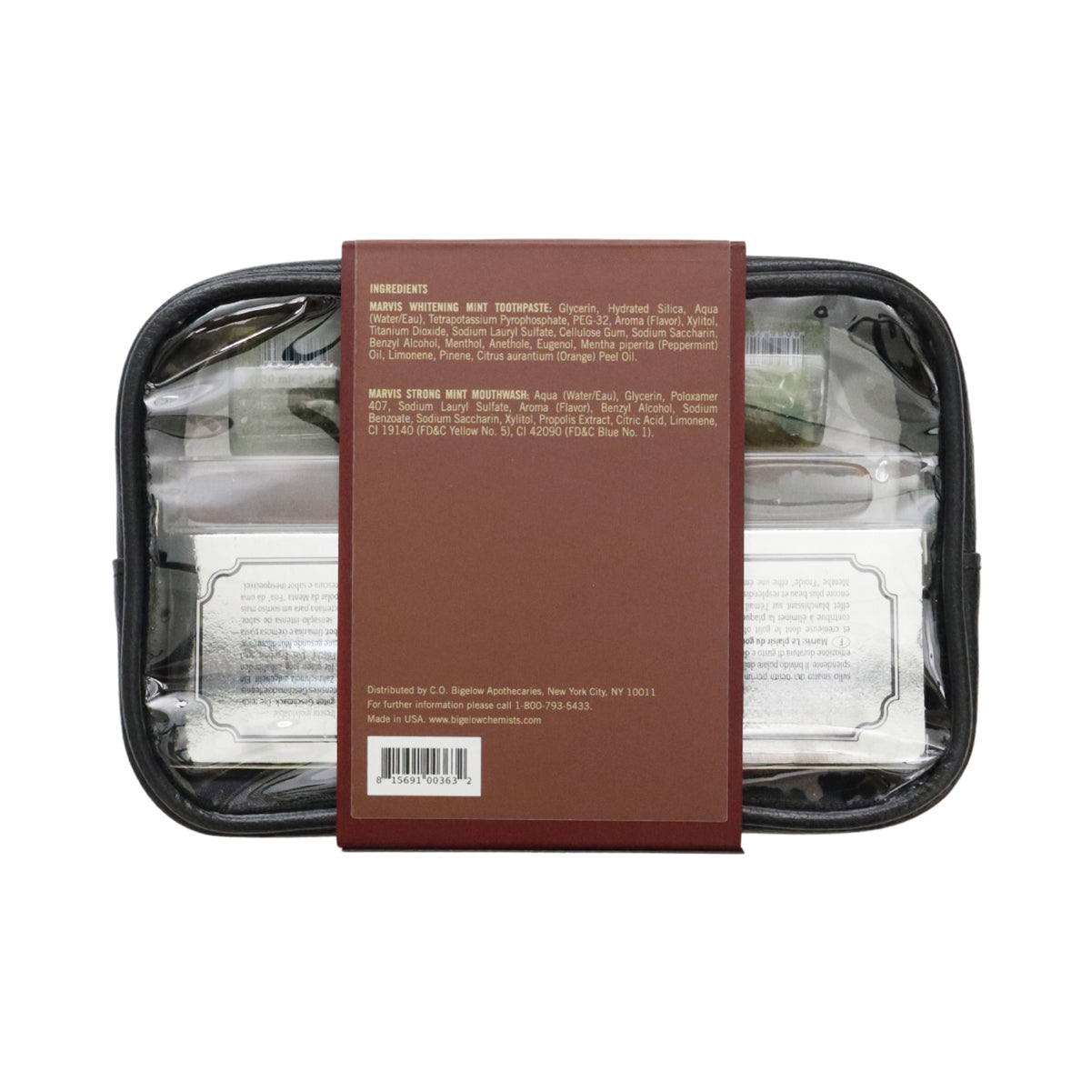 A clear zippered travel toiletry case with a black zipper, shown from the back with a brown paper label covering the center. Inside, several toiletry items are visible through the transparent plastic, including a white bottle and a green packet.