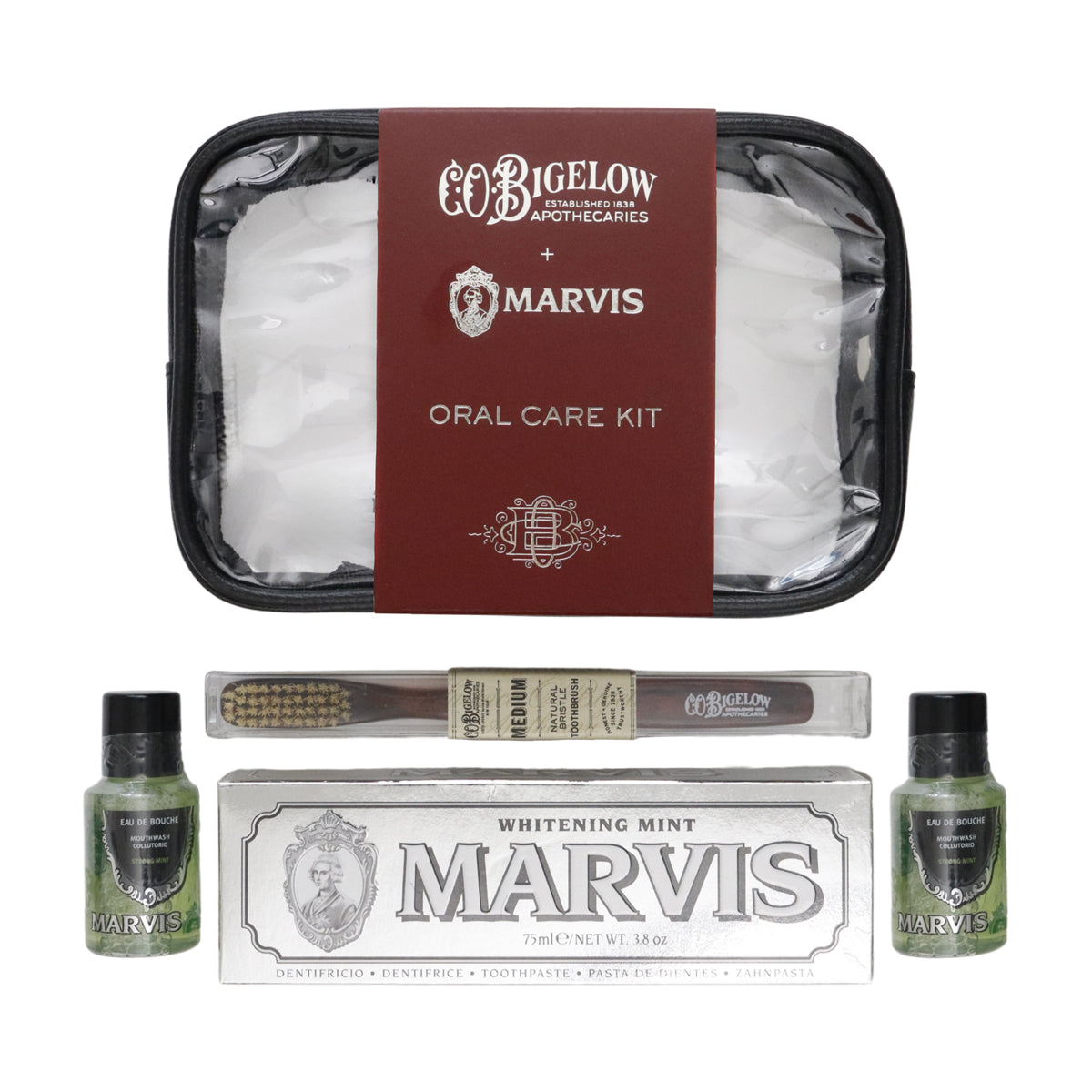 CoBigelow Apothecaries and Marvis Oral Care Kit featuring a black zippered case with a burgundy label, a toothbrush, a box of Whitening Mint toothpaste, and two small green liquid bottles on a white background.