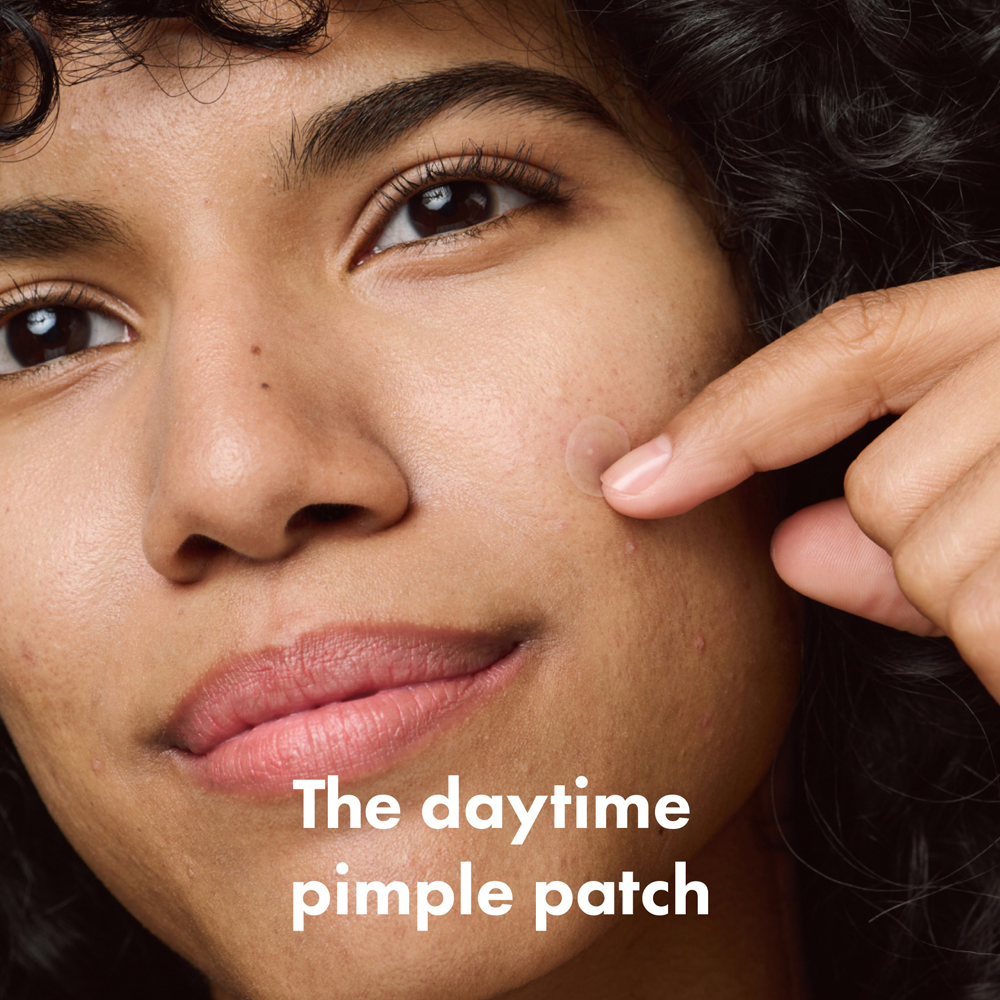 Woman pointing to a pimple on her face with text 'The daytime pimple patch' below.