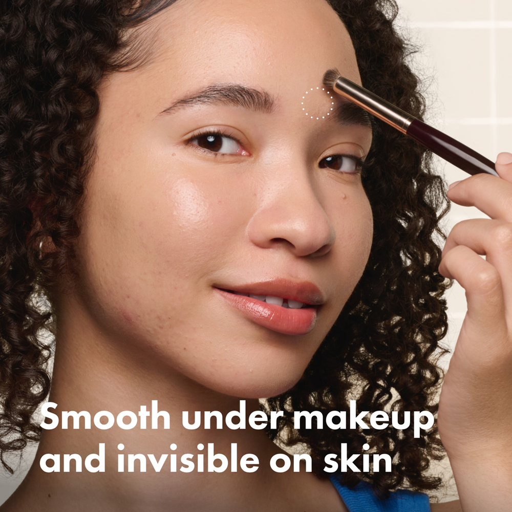 Woman applying makeup with a brush, text 'Smooth under makeup and invisible on skin' displayed.