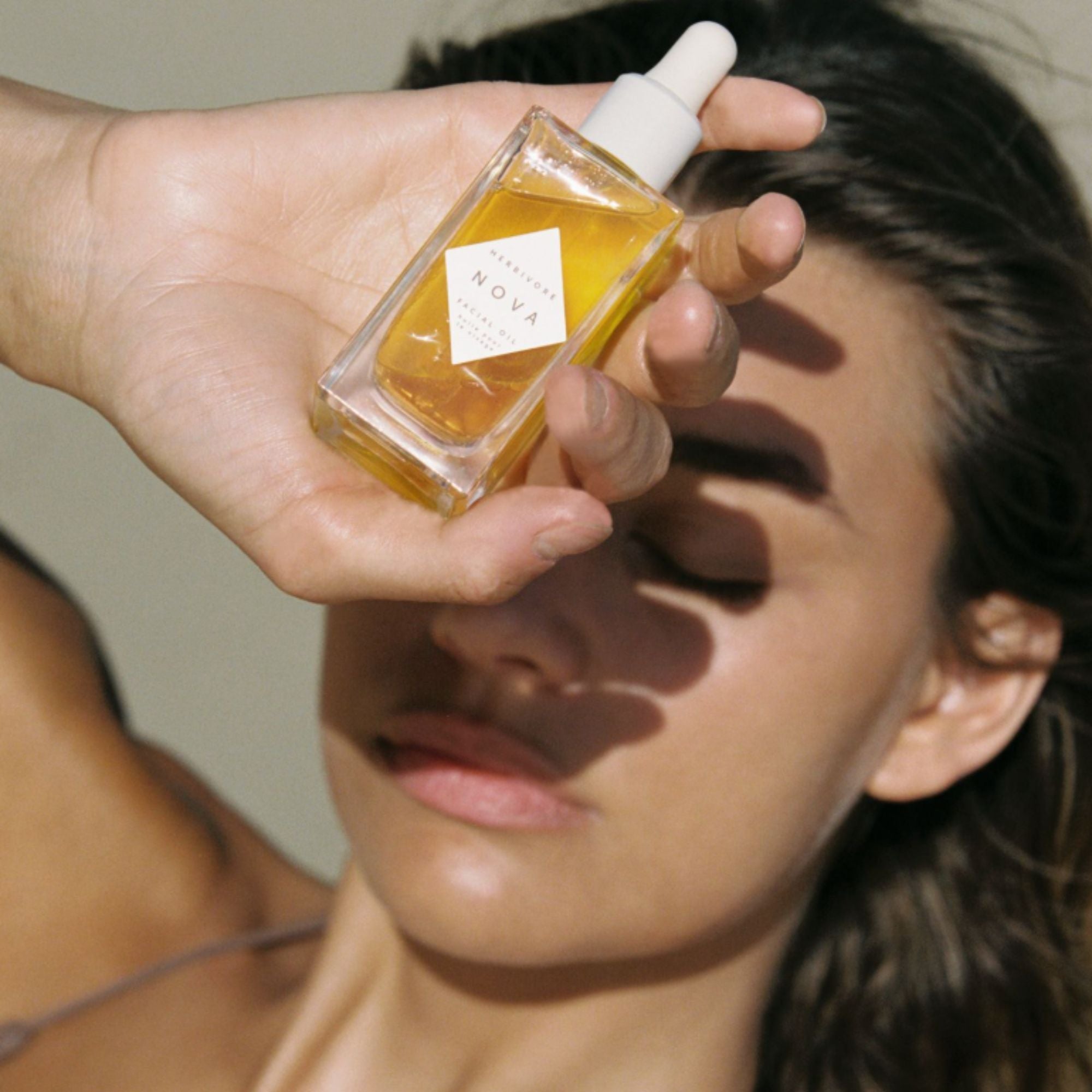 Person holding a small bottle of Nova Oil to their face