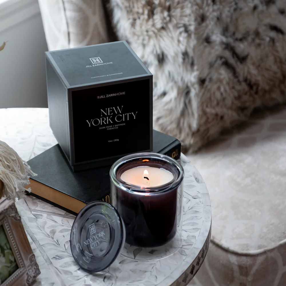 Candle and packaging on a table with a textured sofa in the background