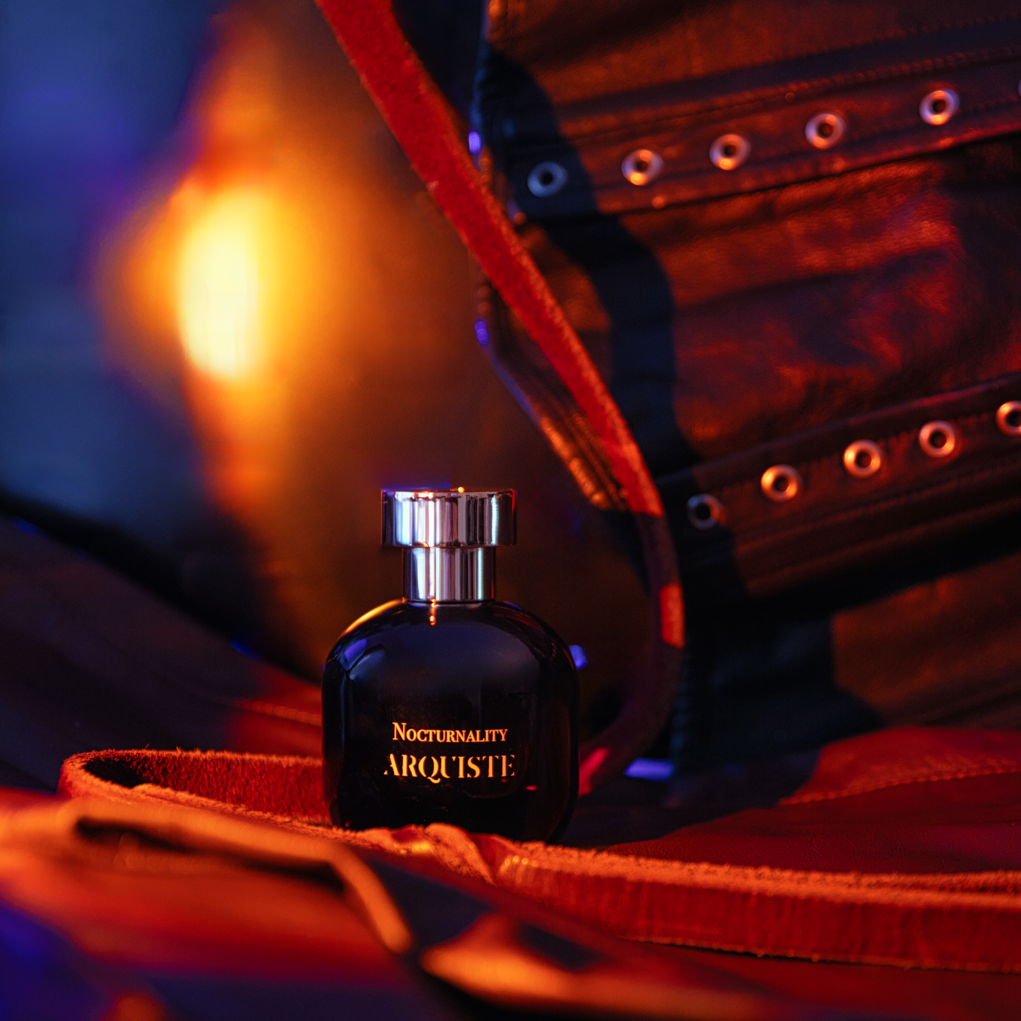Arquiste Perfume bottle on a red leather surface with a blurred background