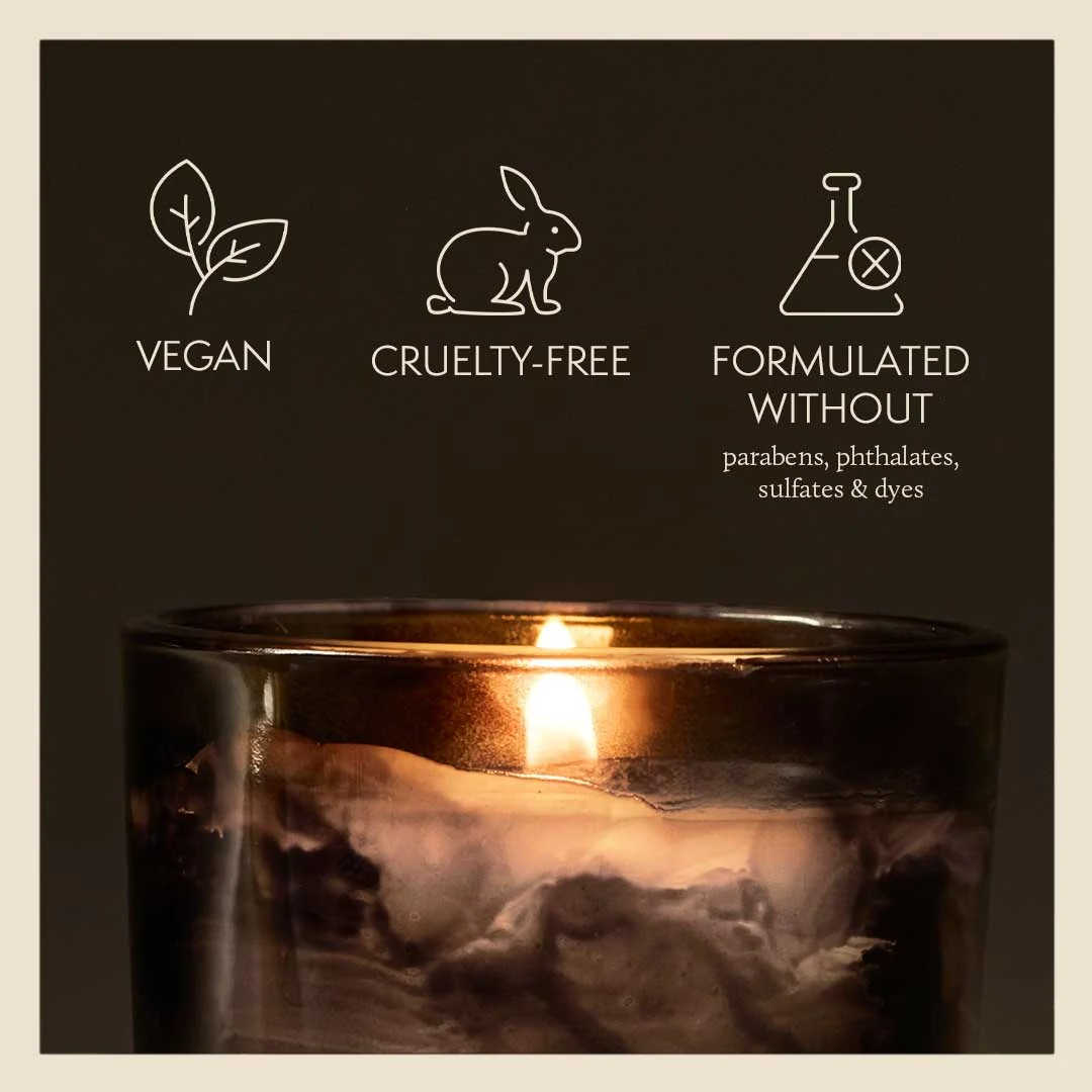 Candle with vegan, cruelty-free, and sulfate-free icons on a dark background