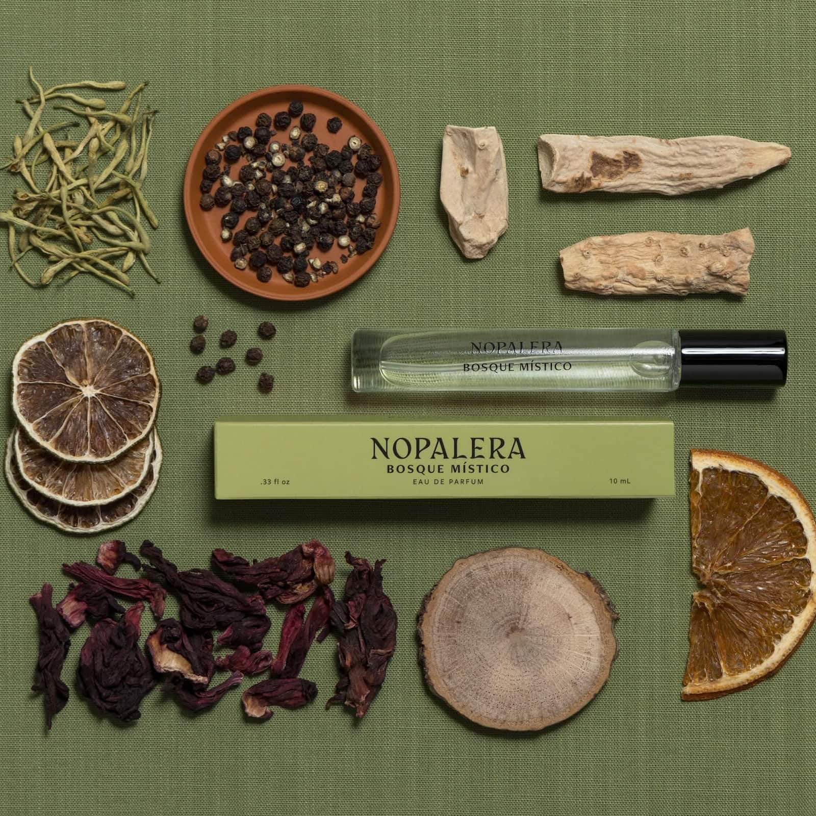 Nopalera Bosque Mistico rollerball surrounded by fragrance notes like all spice, limes, and hibiscus 