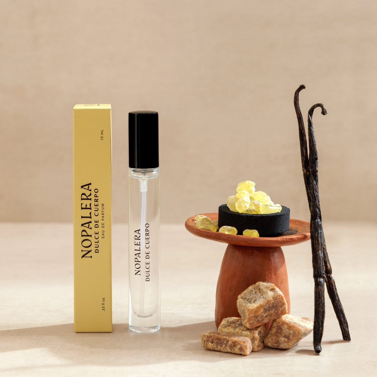 Nopalera perfume bottle with packaging, vanilla beans, and soap on a beige background