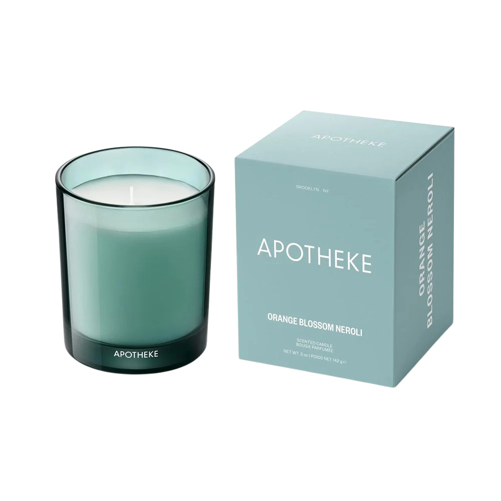 Green candle in a glass holder with 'Apotheke' branding next to its packaging on a white background.