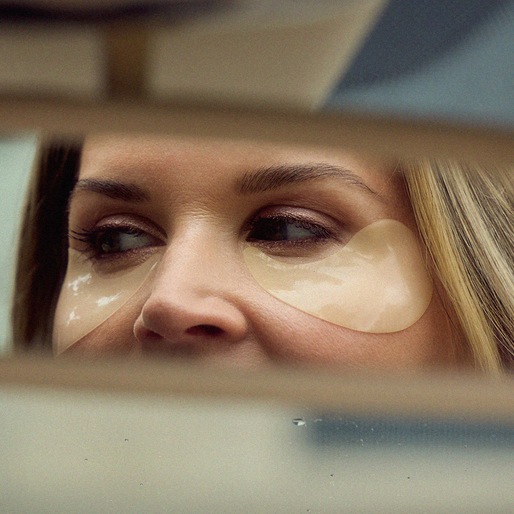 A close-up of a woman's face reflected in a mirror, wearing Radford Patch - the daily mask on her face