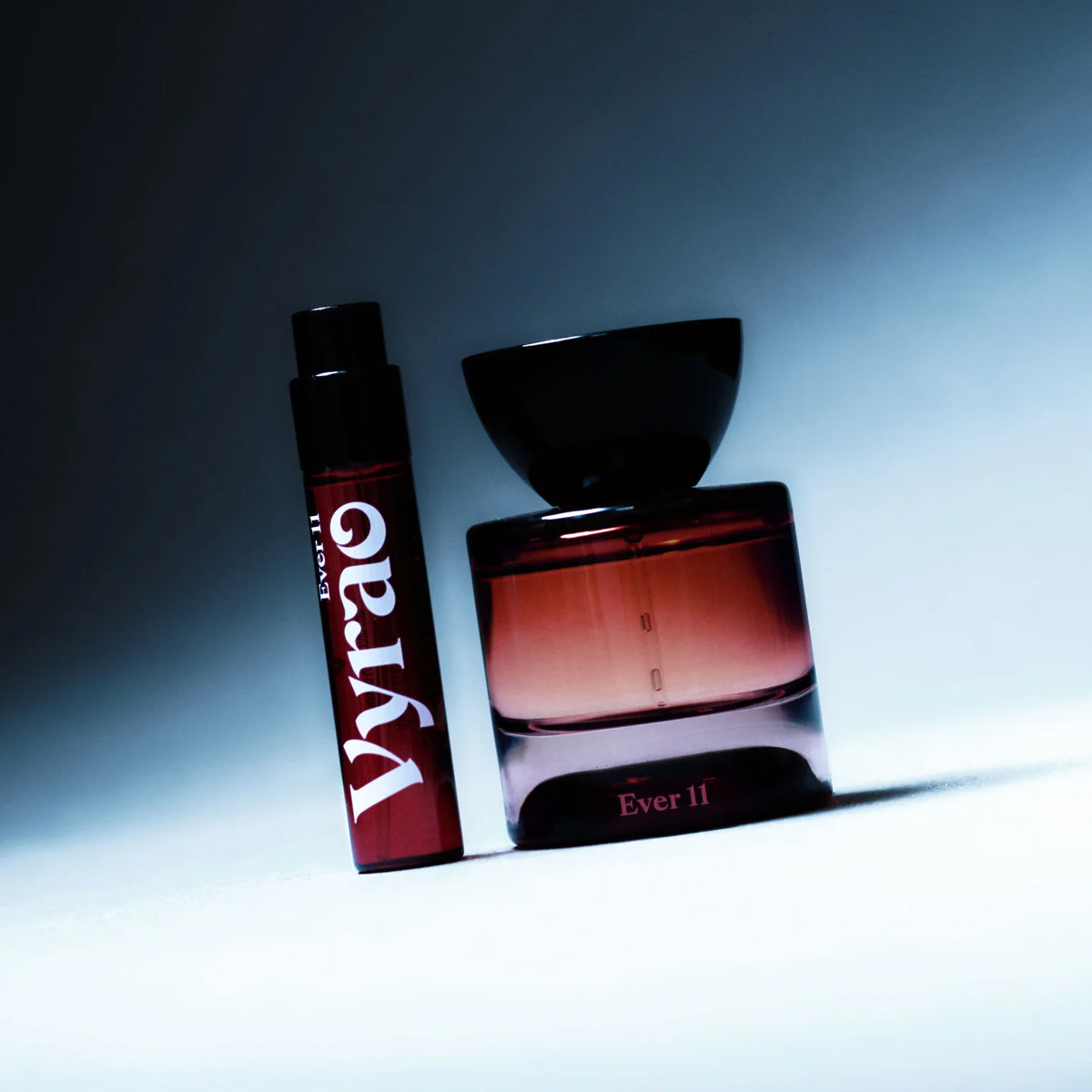 Vyrao EVER 11 Eau de Parfum bottle and smaller diespenser at a dramatic angle in front of a moody gradient background