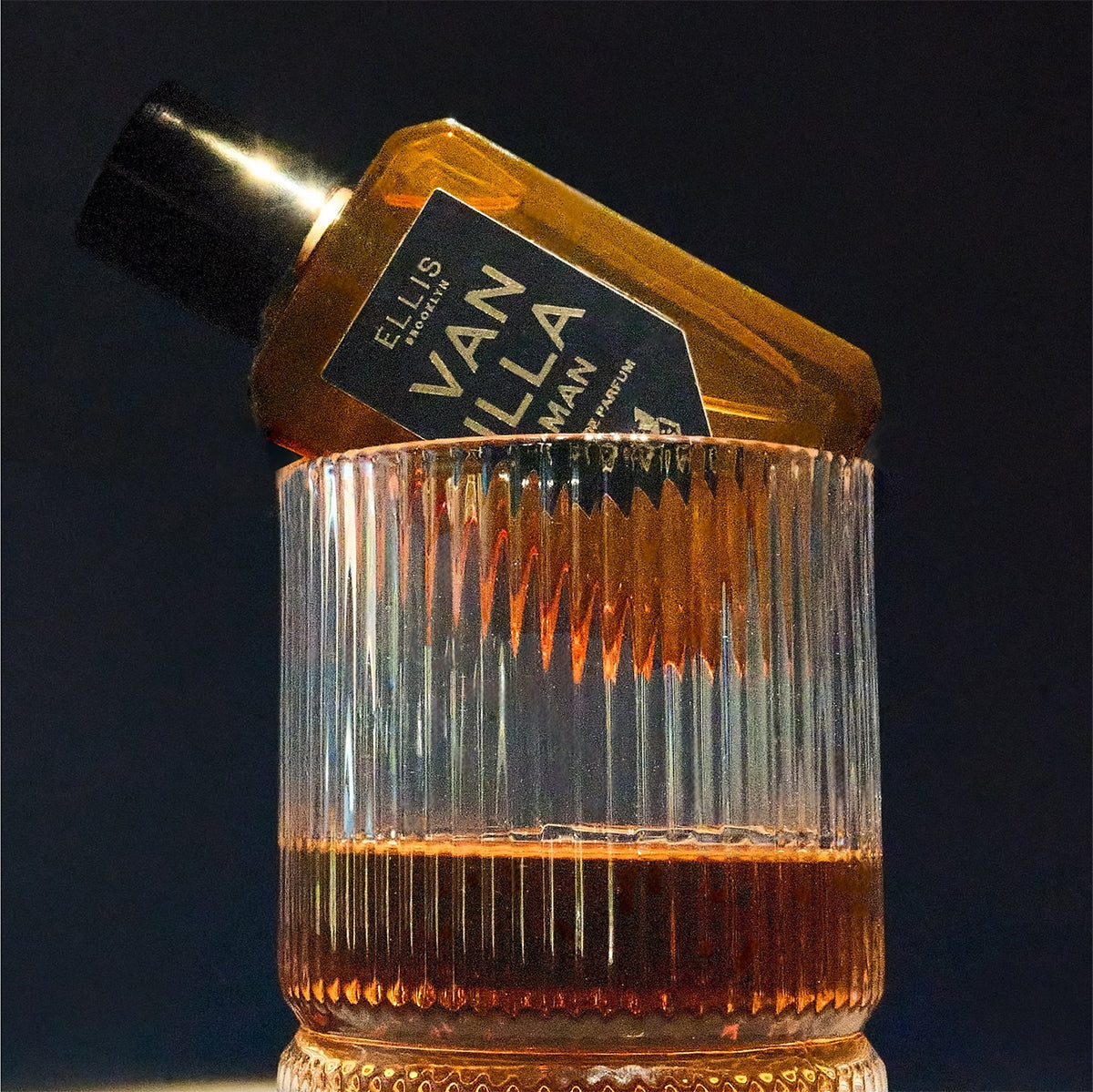 Bottle of Ellis Brooklyn Vanilla Man perfume in a glass with a dark background