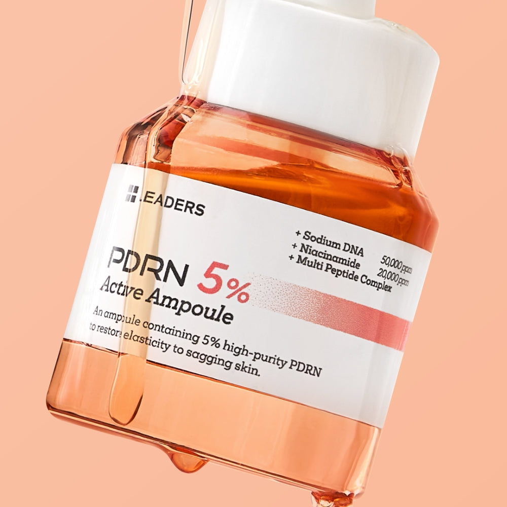 LEADERS PDRN 5% Actue Ampoule skincare bottle filled with peach-colored liquid, shown at an angle against a solid peach background.