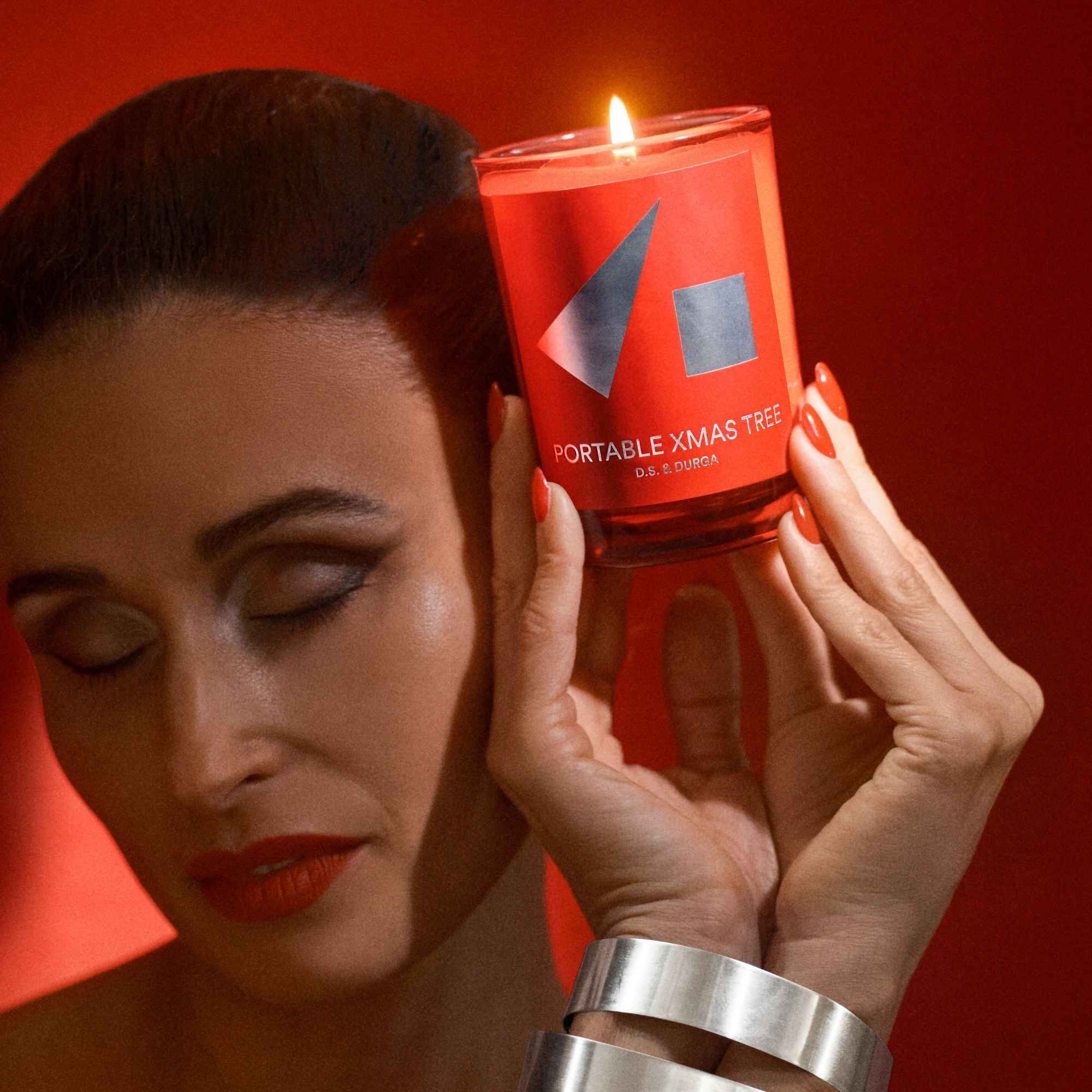 Woman holding a red candle labeled 'Portable Xmas Tree' against a red background