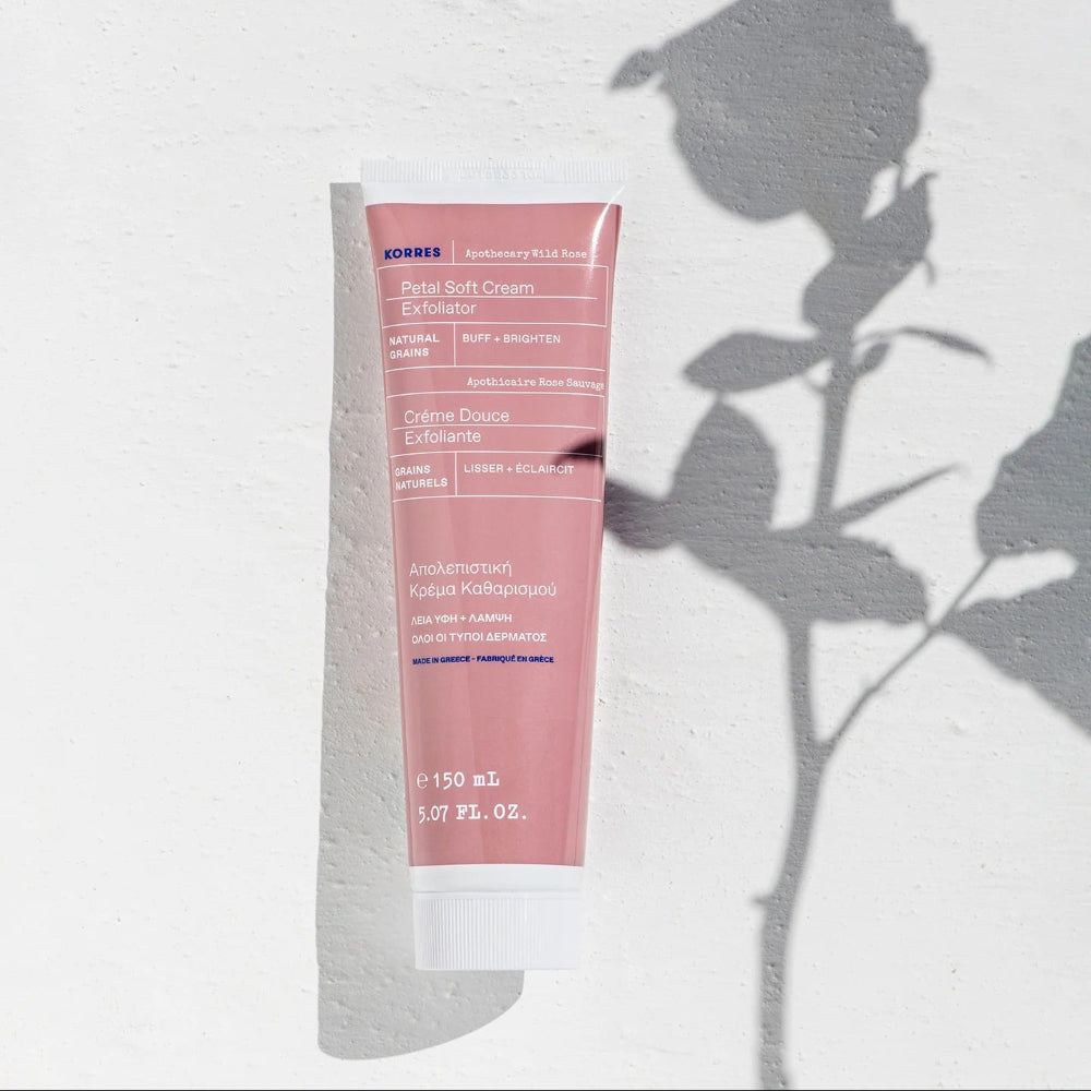 Tube of Korres Petal Soft Cream Exfoliant on a white background with a floral shadow.