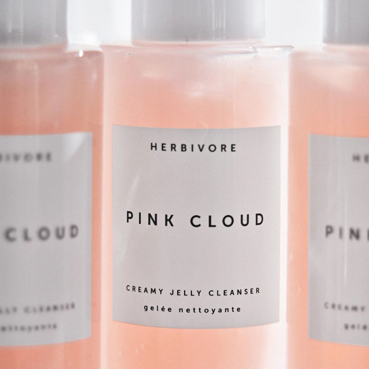 Three bottles of Herbivore Pink Cloud Creamy Jelly Cleanser on a light background
