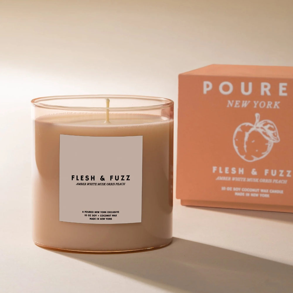 Candle labeled 'Flesh & Fuzz' with a matching box on a neutral background
